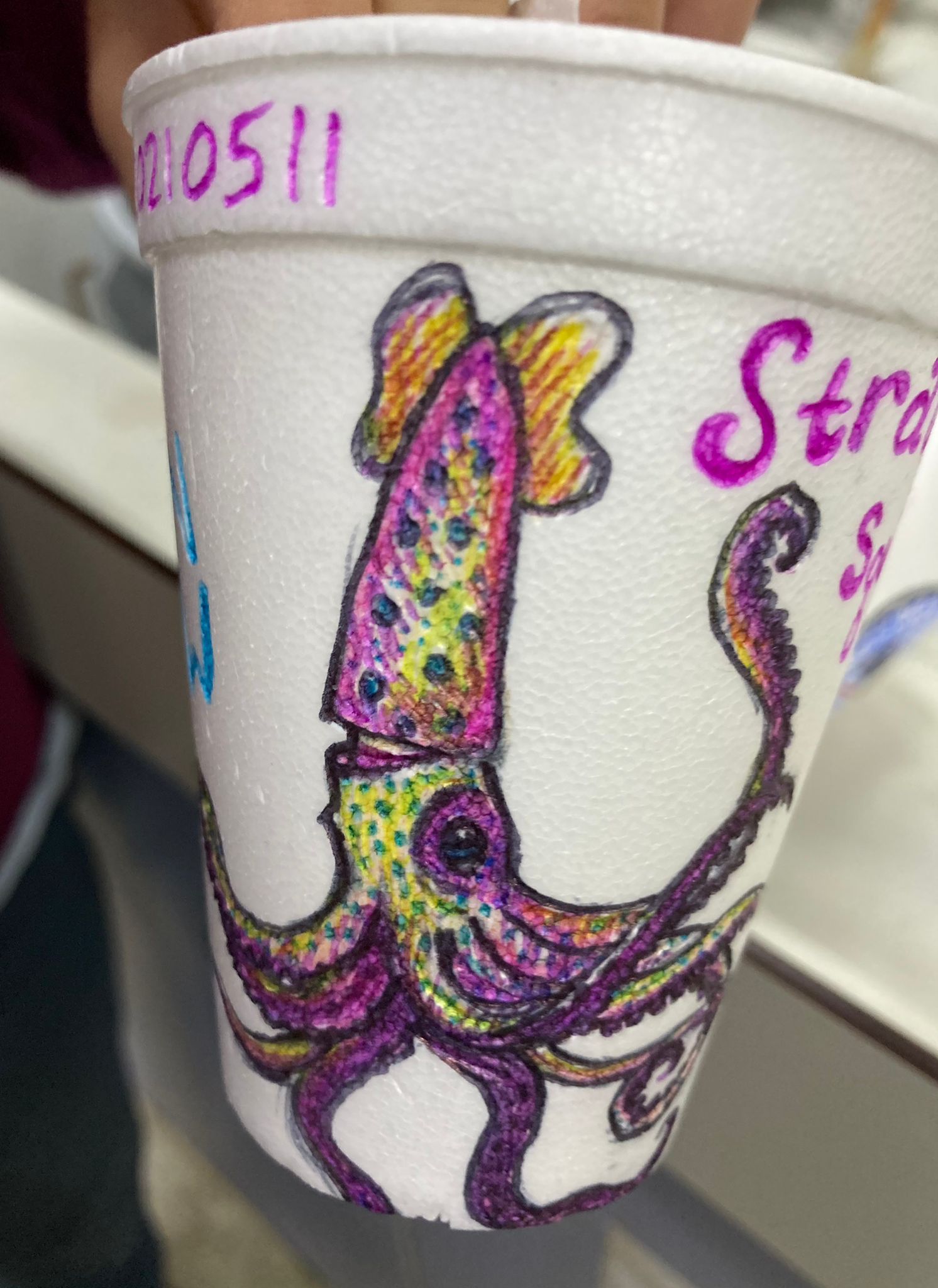 A strawberry squid illustrated by Julia Cox adorns a Styrofoam cup that was crushed under ocean pressure after hitching a ride to the twilight zone on a CTD rosette. Photo by Michelle Cusolito, Woods Hole Oceanographic Institution.