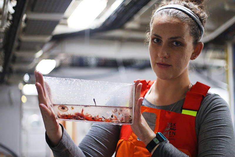 Kayla Gardner holds a container of specimens from the ocean twilight zone. Photo by Marley Parker, @Woods Hole Oceanographic Institution
